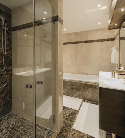 Modern bathroom with marble shower, dual sinks, and LED lighting