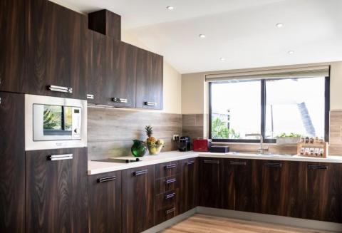 Modern kitchen with dark wood cabinets, stainless appliances, and pops of red.