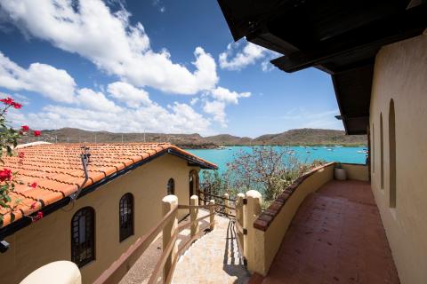View from a Mediterranean balcony overlooking a bay with boats and hills