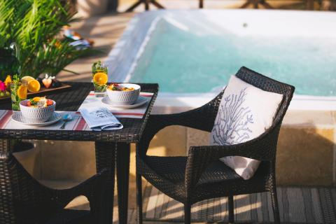 Outdoor poolside dining setup with healthy meals, cocktails, and fruit plate.