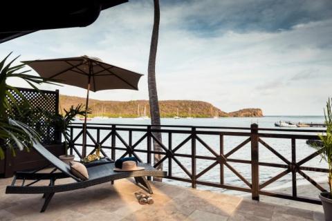 Relaxation area with lounge bed overlooking a scenic bay with boats and hills.