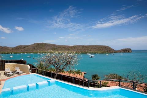 Luxury infinity pool overlooking a yacht-filled blue bay and lush hills