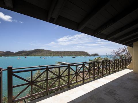 Serene waterside view from a covered terrace with boats and rolling hills.