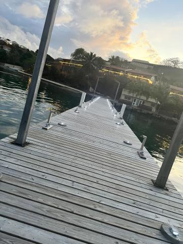 Sunset at marina with wooden dock, palm trees, and waterfront building, peaceful scene