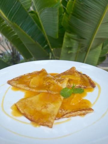 Golden-brown triangular pastries with orange syrup and a mint leaf on a plate