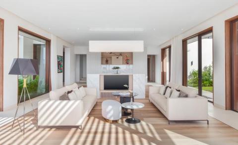 Modern living room with large windows, beige sofa, and wooden accents for a cozy home.