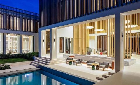 Modern luxury home with pool and outdoor seating area illuminated at dusk.