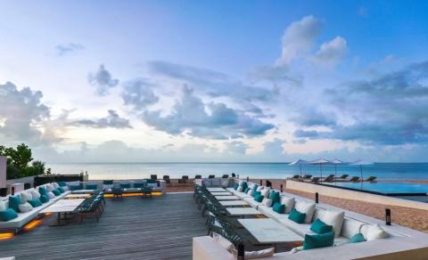 Luxurious beachfront terrace with elegant furniture and ocean view at dusk.