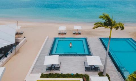 Luxurious beachfront with pools, sandy beach, and palm trees, ideal for serene vacations.
