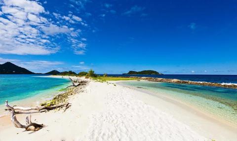 Tropical beach with turquoise waters and lush green hills, serene blue skies above