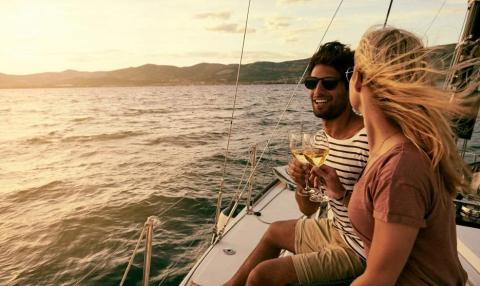 Two people enjoying wine on a boat at sunset with hills in the background