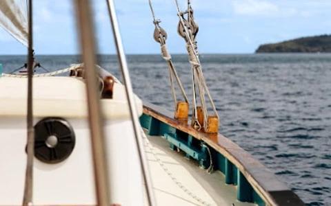 Sailing boat deck with wet surface, metal railings, and open sea view