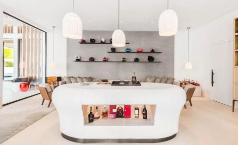 Modern bar with gray bench, handbag shelves, and pod lights in an elegant room.