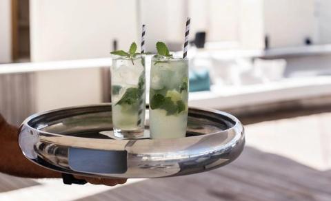Two mojitos on a tray, outdoor setting with blurred architecture backdrop