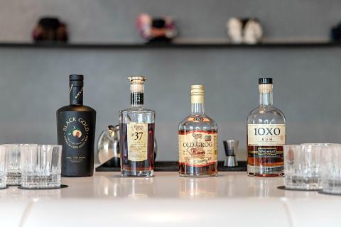 Assorted rum bottles including Black Gold, Old Grog, and 10XO on reflective surface