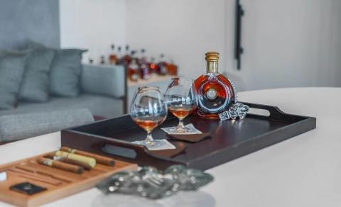 Elegant setup with cognac glasses, cigars on tray, luxury interior backdrop.