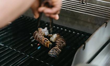 Grilling skewered vegetables with tongs over a barbecue grill