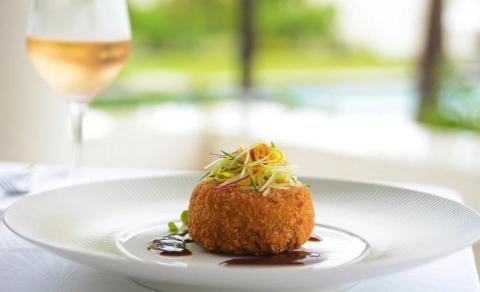 Gourmet fried food with colorful vegetables and sauce, wine and luxury outdoor setting.