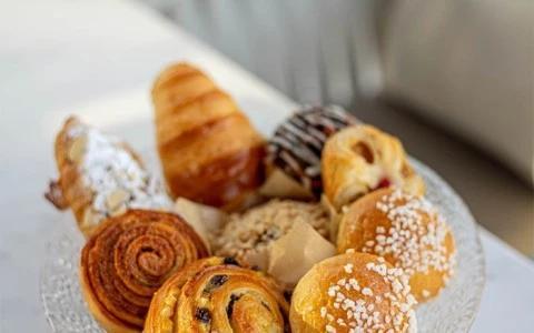 Assorted pastries on a plate, including croissants and Danishes, in an elegant setting