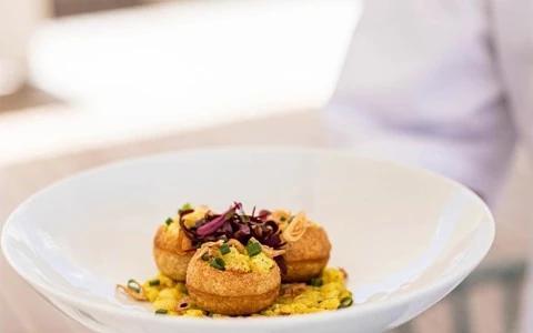 Gourmet fritters on yellow grains with magenta leaves, elegant presentation