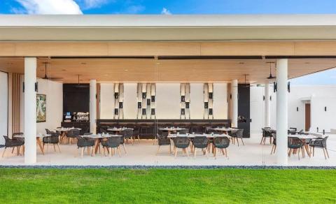 Modern outdoor dining area with stylish chairs and green lawn at upscale restaurant