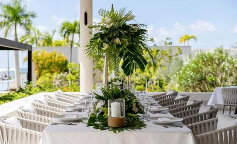 Elegant outdoor dining setup with lush floral centerpiece and coastal view
