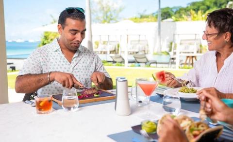 Man and woman dining seaside with cocktails and pasta at resort-like restaurant