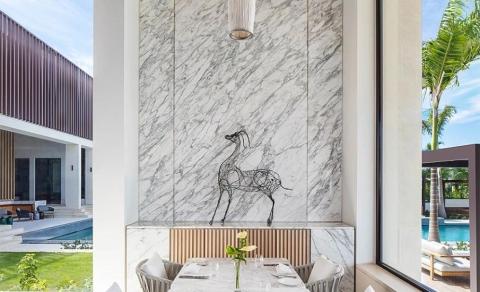 Luxurious dining room with marble wall, horse sculpture, and pool view