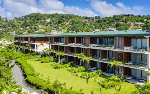 Modern resort with lush gardens and palm trees, hill backdrop