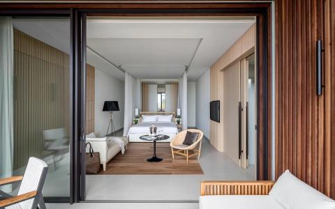 Modern hotel room with a large bed, wooden decor, and balcony view.