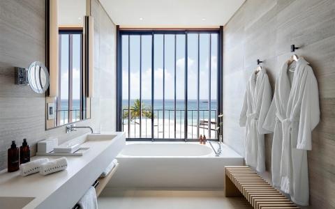 Modern bathroom with ocean view, sleek bathtub, and plush robes.