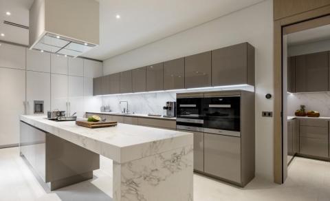 Modern minimalist kitchen with grey cabinets, marble counters, and built-in appliances.