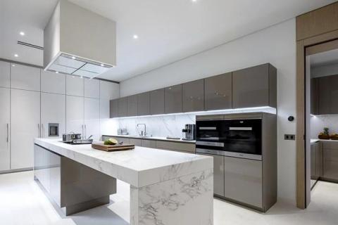 Modern kitchen with gray cabinets, marble island, and integrated appliances.