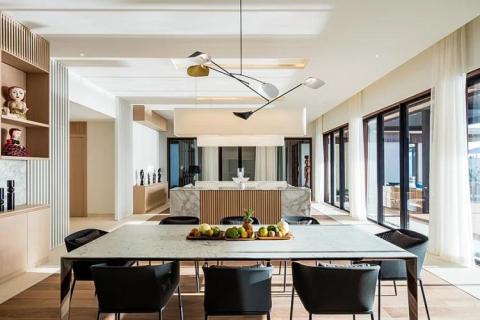 Modern kitchen with island, wooden cabinets, and artistic light over dining table.