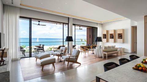 Modern living room with ocean view, wooden furniture, and marble kitchen counter.