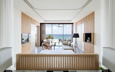 Modern sea-view room with balcony, stylish decor, and beach vista