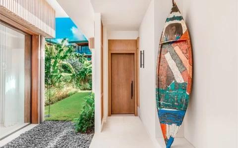 Modern hallway with surfboard decor and garden view through glass windows.