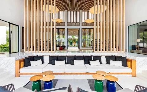 Modern interior with white couches, colorful stools, and glass doors opening outdoors.