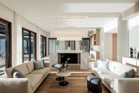 Modern living room with gray sofas, marble fireplace, and large windows