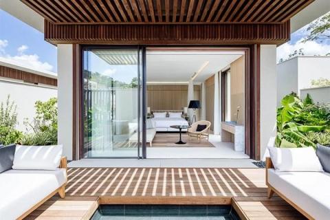 Stylish outdoor-indoor seating area with white sofas and wooden accents.