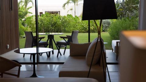 Stylish interior with beige couch and lush garden view through sliding doors.