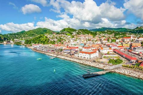 Colorful coastal town with sea, boats, and green hills under a cloudy sky
