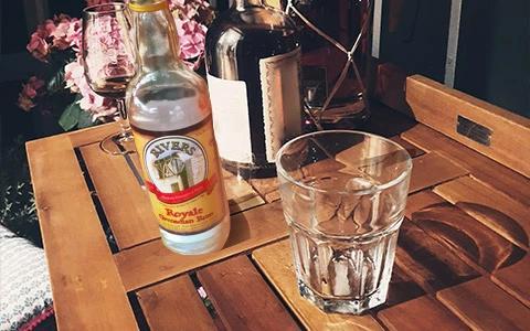 Royale Vermouth on table with ice-filled glass and floral backdrop in garden setting