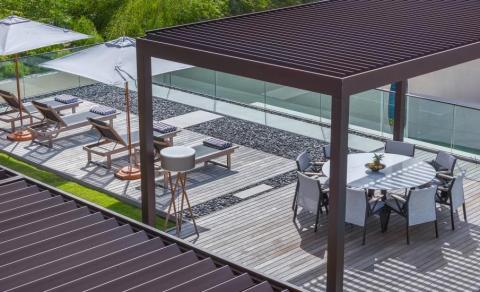 Modern outdoor patio with dining area, lounge chairs, pool, and pergola.