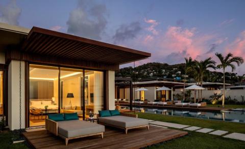Luxurious modern villa with pool at dusk, pink sky backdrop, hillside view
