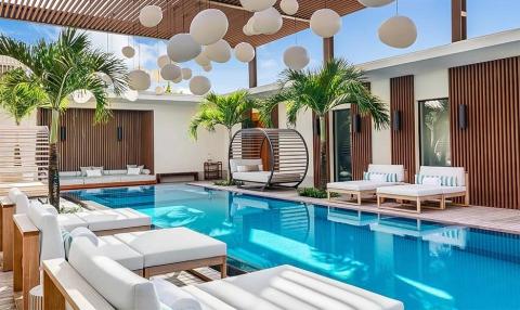 Luxury outdoor pool with white chairs, swinging bed, and palm trees, contemporary design.