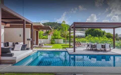 Luxury outdoor pool area with seating, dining setup, and greenery, perfect for relaxation