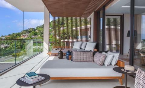 Luxurious daybed on terrace with green landscape view, ideal for relaxation.