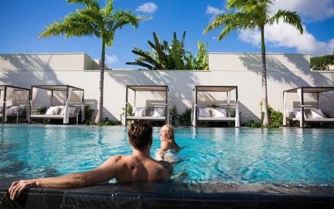 Luxury pool with couple, cabanas, and palms, clear sky