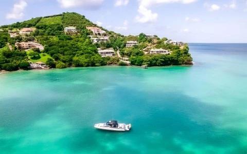 Scenic coastal view with a white boat, turquoise waters, and hillside villas